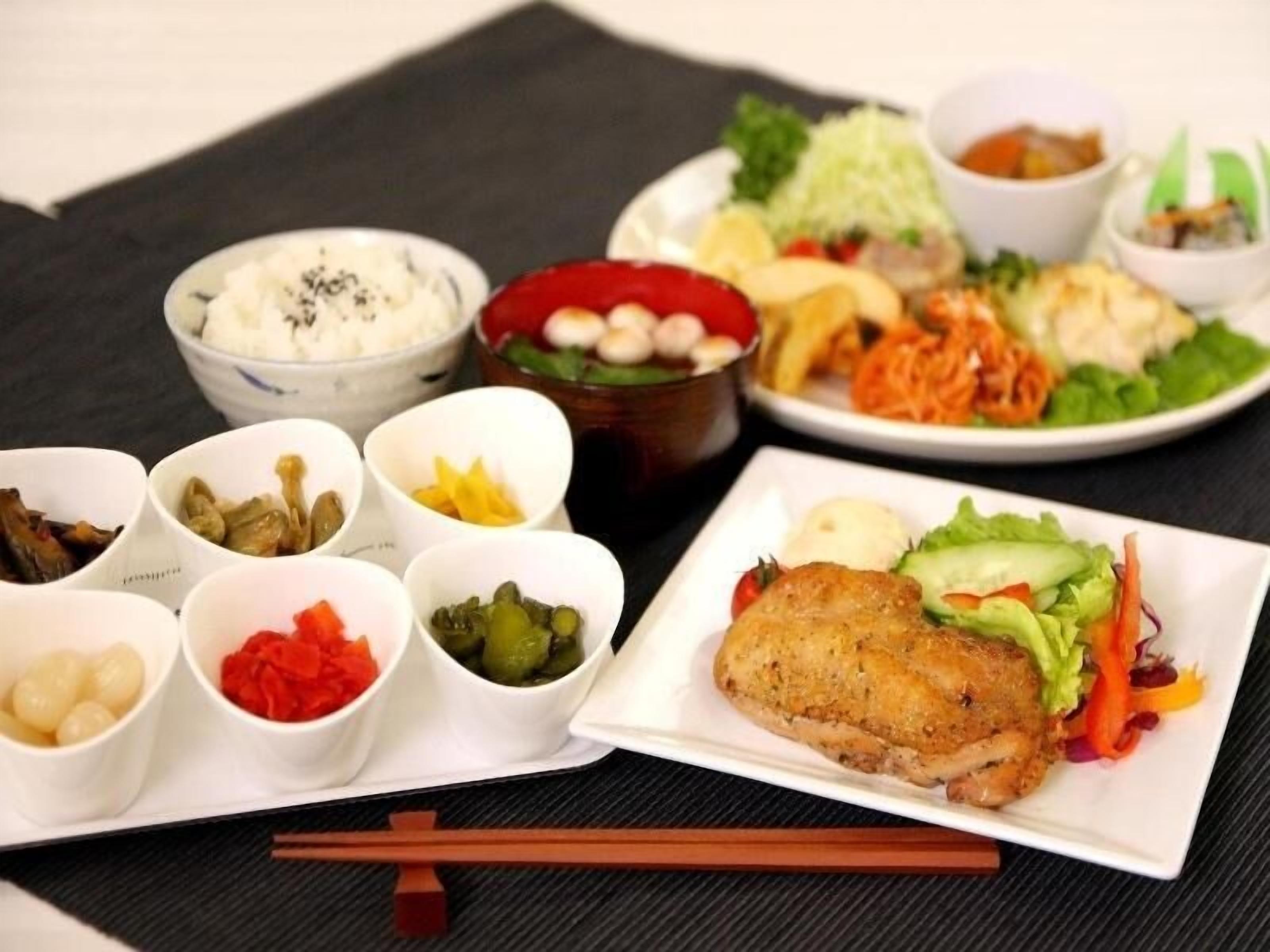 Un assortiment de plats comprenant un plat principal avec un accompagnement frit, des salades et plusieurs petits bols contenant différentes sauces et condiments.