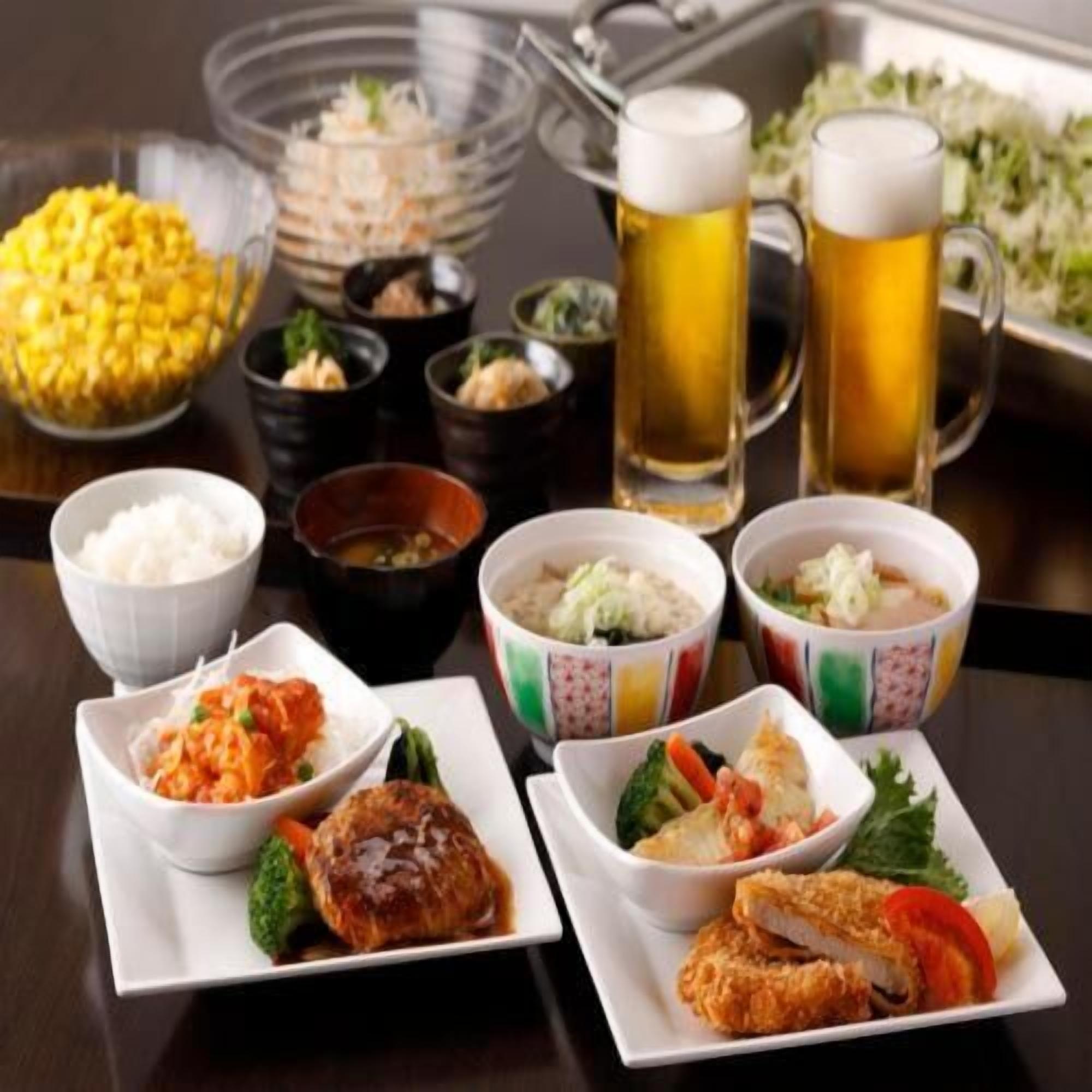 A table set with various dishes, including rice, soup, and meat, along with two beer mugs.