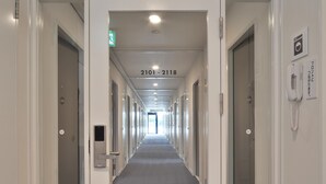 A hotel corridor with doors numbered 2101-2118, a phone on the wall, and an emergency exit sign. - Value The Hotel Sendai Natori (Natori)