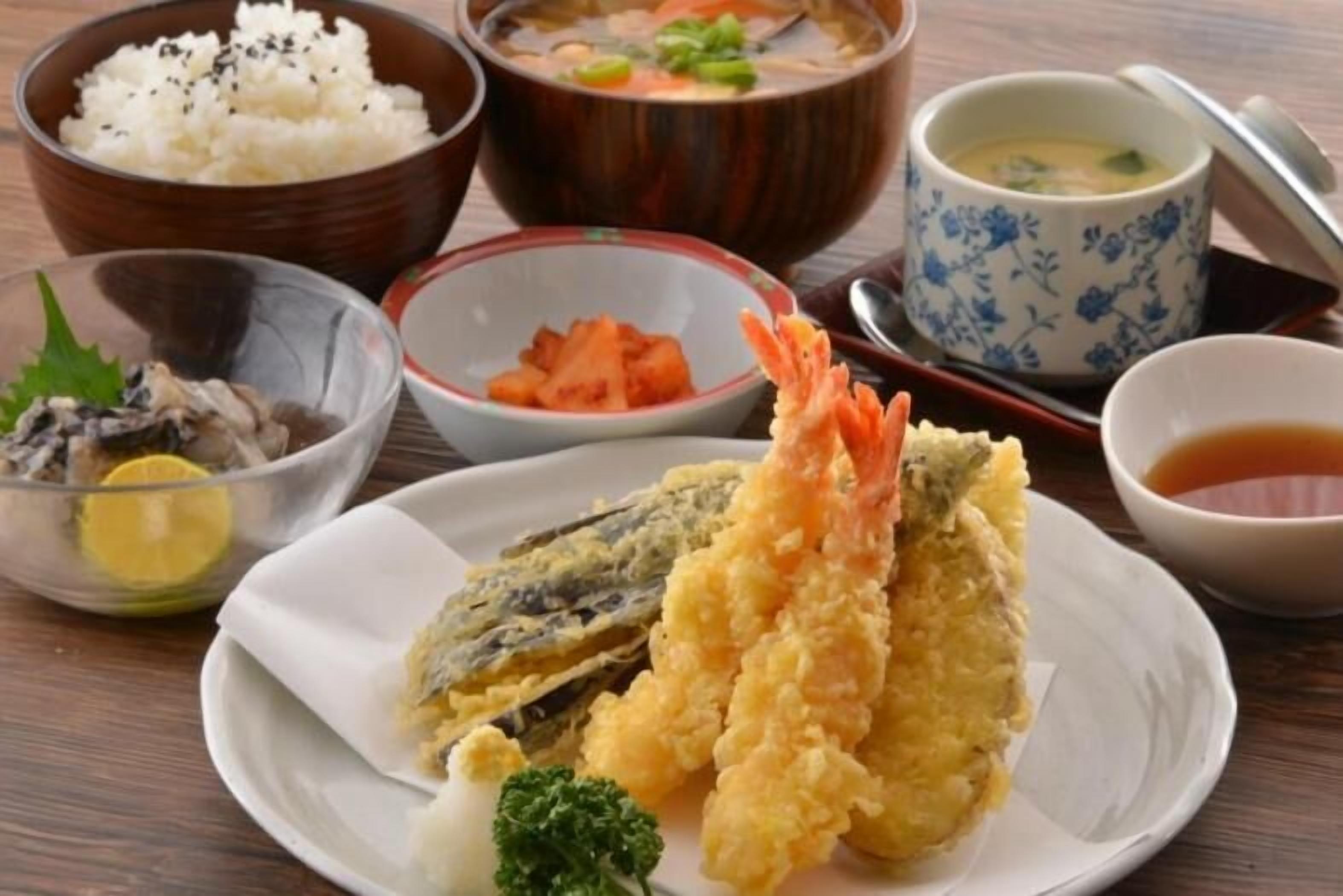 A table with various dishes including tempura, rice, and soup.