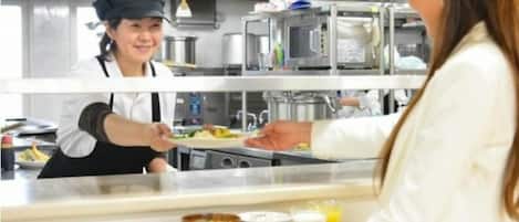 Een keuken met roestvrijstalen apparatuur en een aanrecht waar eten wordt bereid.