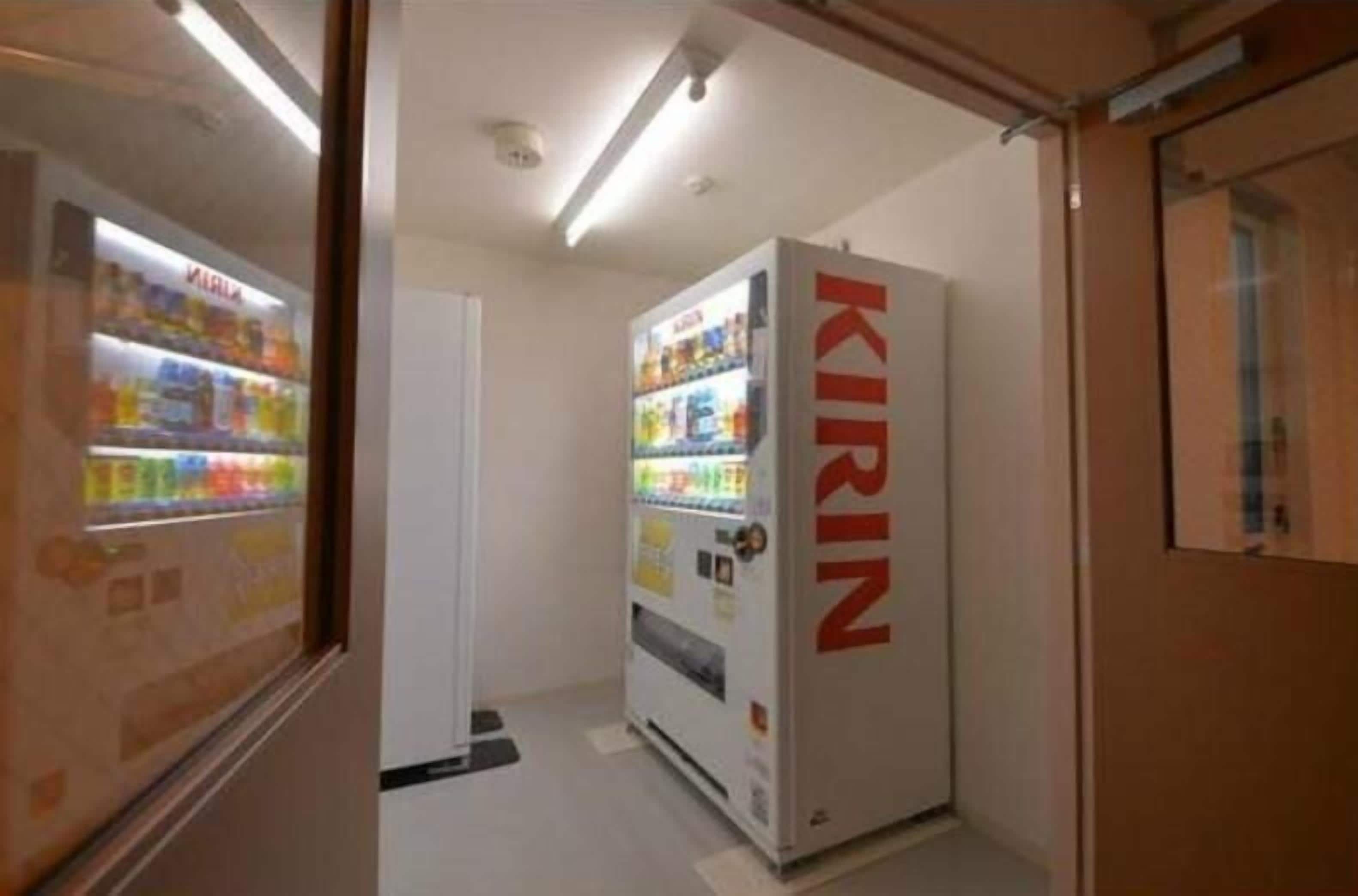 A vending machine labeled 'KIRIN' in a narrow hallway with a door on the right.