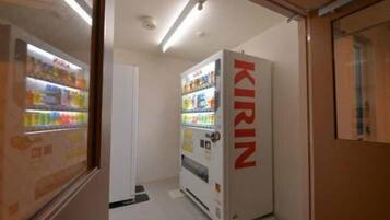 A vending machine labeled 'KIRIN' in a narrow hallway with a door on the right.
