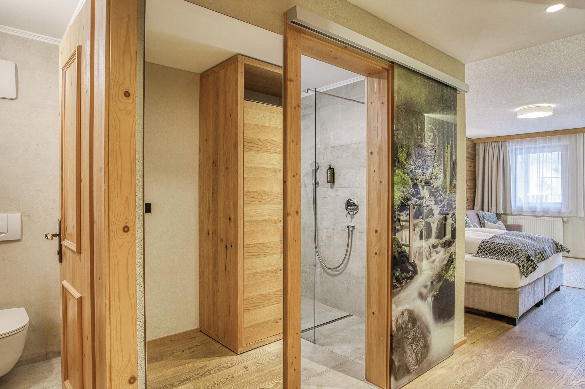 Un dormitorio moderno con ducha de vidrio, armario de madera y cama con vistas al exterior.