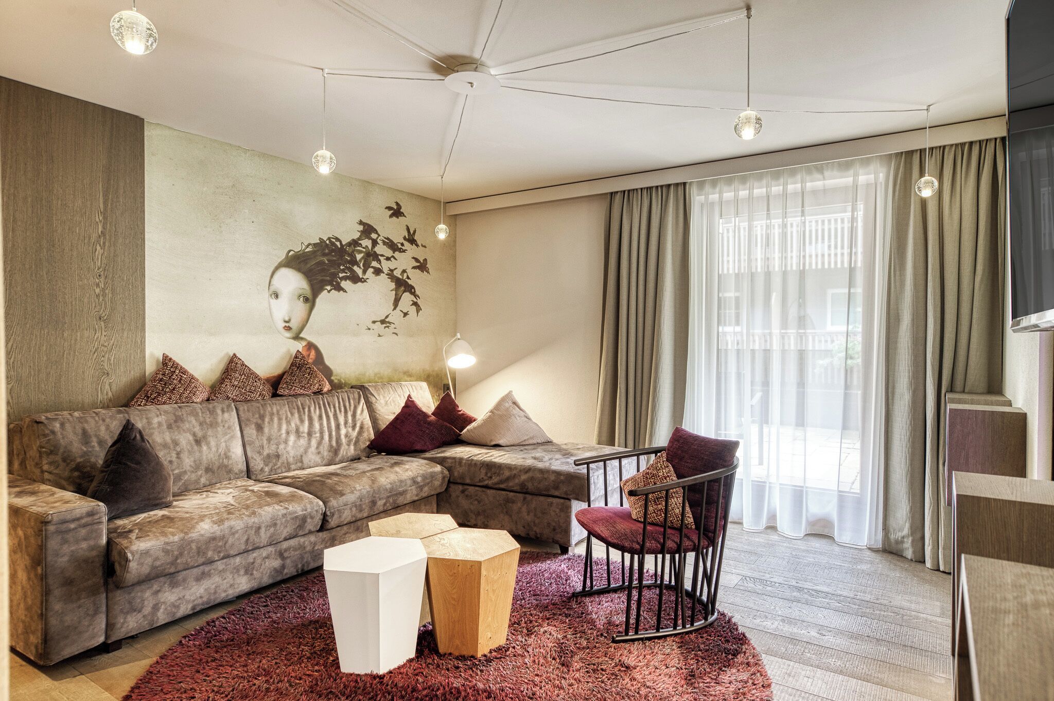 A modern living room with a sectional sofa, a small table, a chair, a rug, and a wall-mounted artwork.