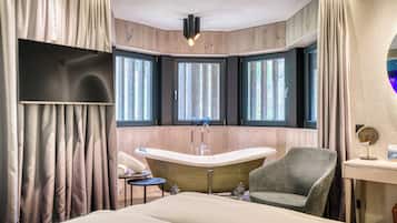 A modern bathroom with a freestanding bathtub, a vanity with a mirror, and a window with curtains.