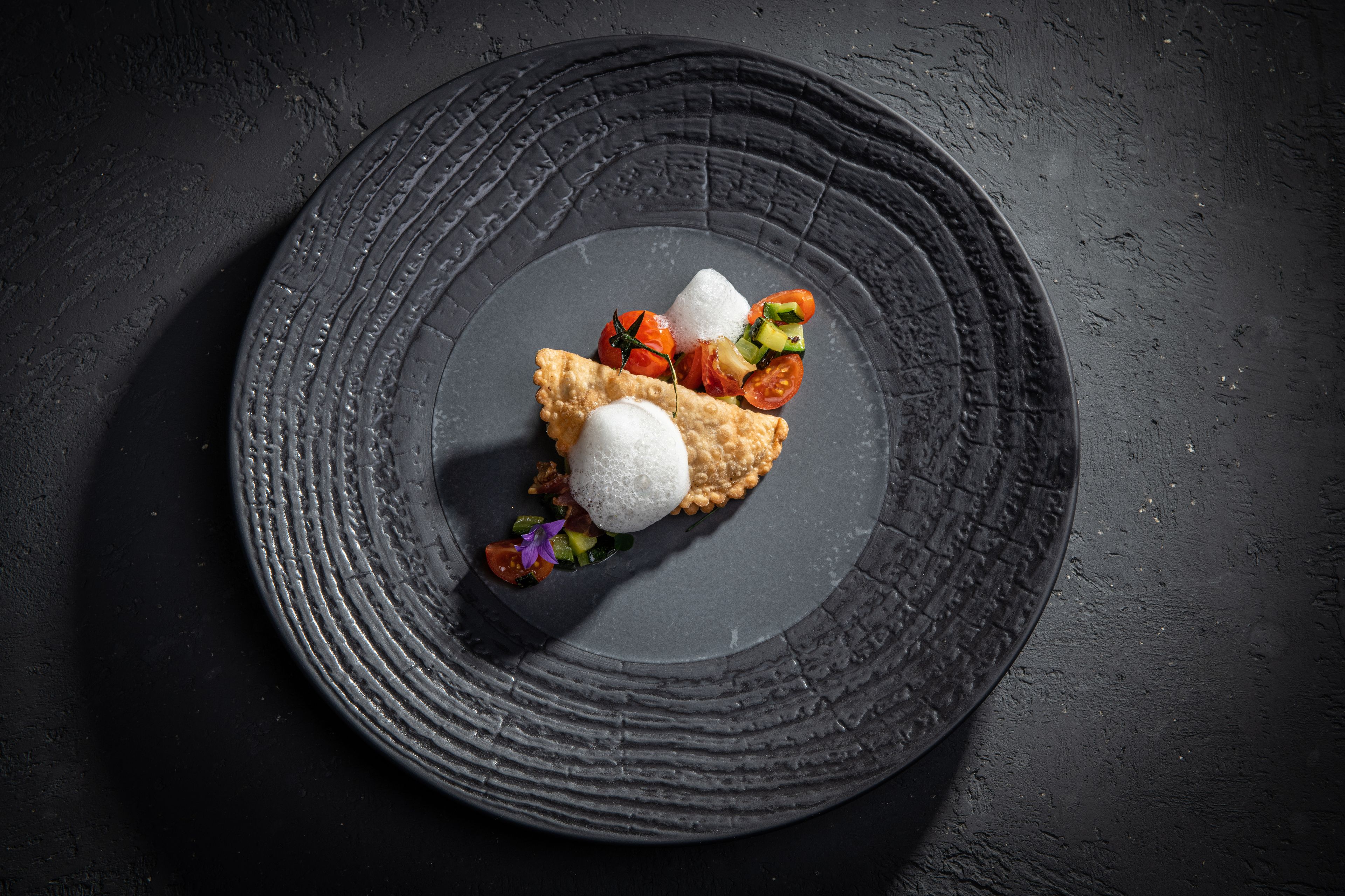 A dessert on a textured plate with a dark background.