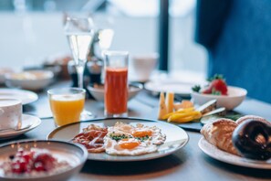 A breakfast table with various dishes including eggs, bacon, croissants, and fruit. - ZillergrundRock Luxury Mountain Resort (Mayrhofen)