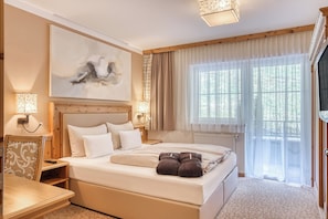 A bedroom with a large bed, bedside tables, a wall-mounted lamp, and a window with curtains. - ZillergrundRock Luxury Mountain Resort (Mayrhofen)
