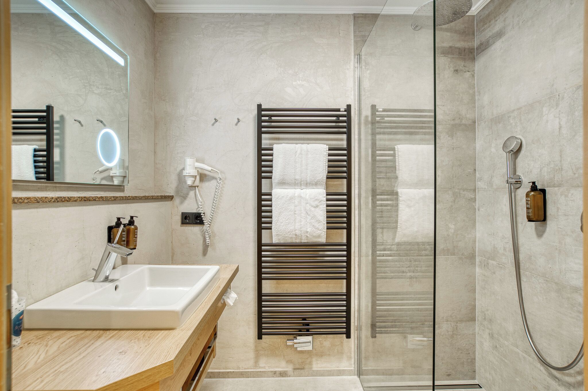 Un baño moderno con lavamanos, espejo, toallero y ducha.