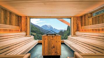 A sauna with wooden benches and a view of mountains through large windows.