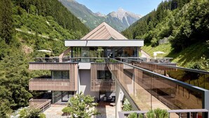 Ein modernes, mehrgeschossiges Gebäude mit einem zentralen Atrium, umgeben von üppiger Vegetation und Bergen.