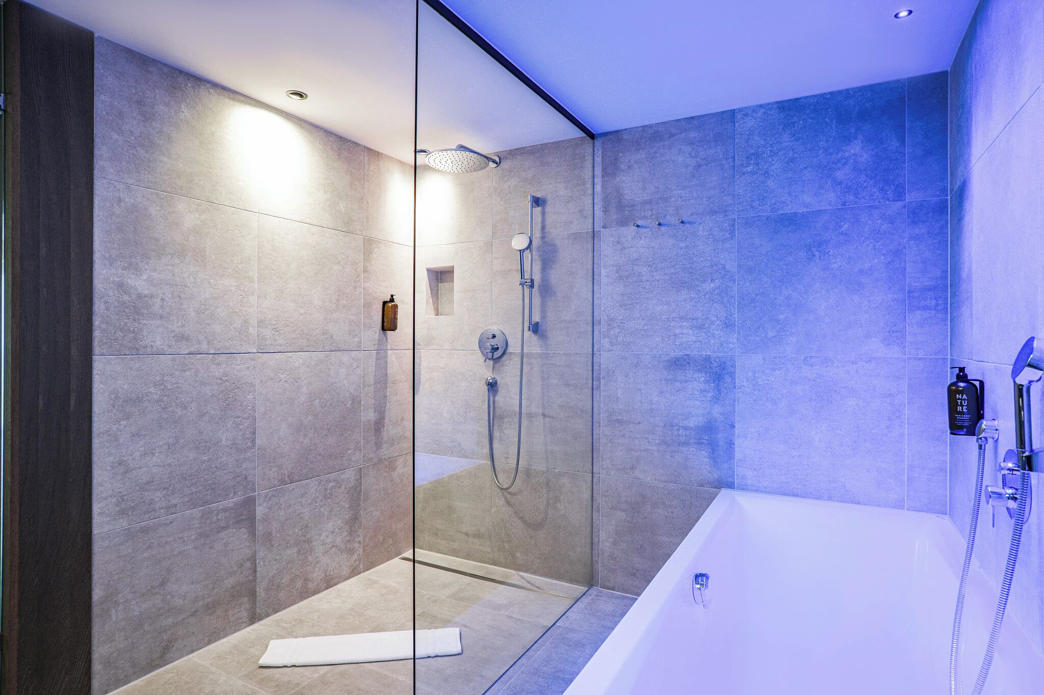 A modern bathroom with a glass-enclosed shower, a standalone bathtub, and a wall-mounted faucet.