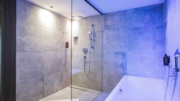 A modern bathroom with a glass-enclosed shower, a standalone bathtub, and a wall-mounted faucet.