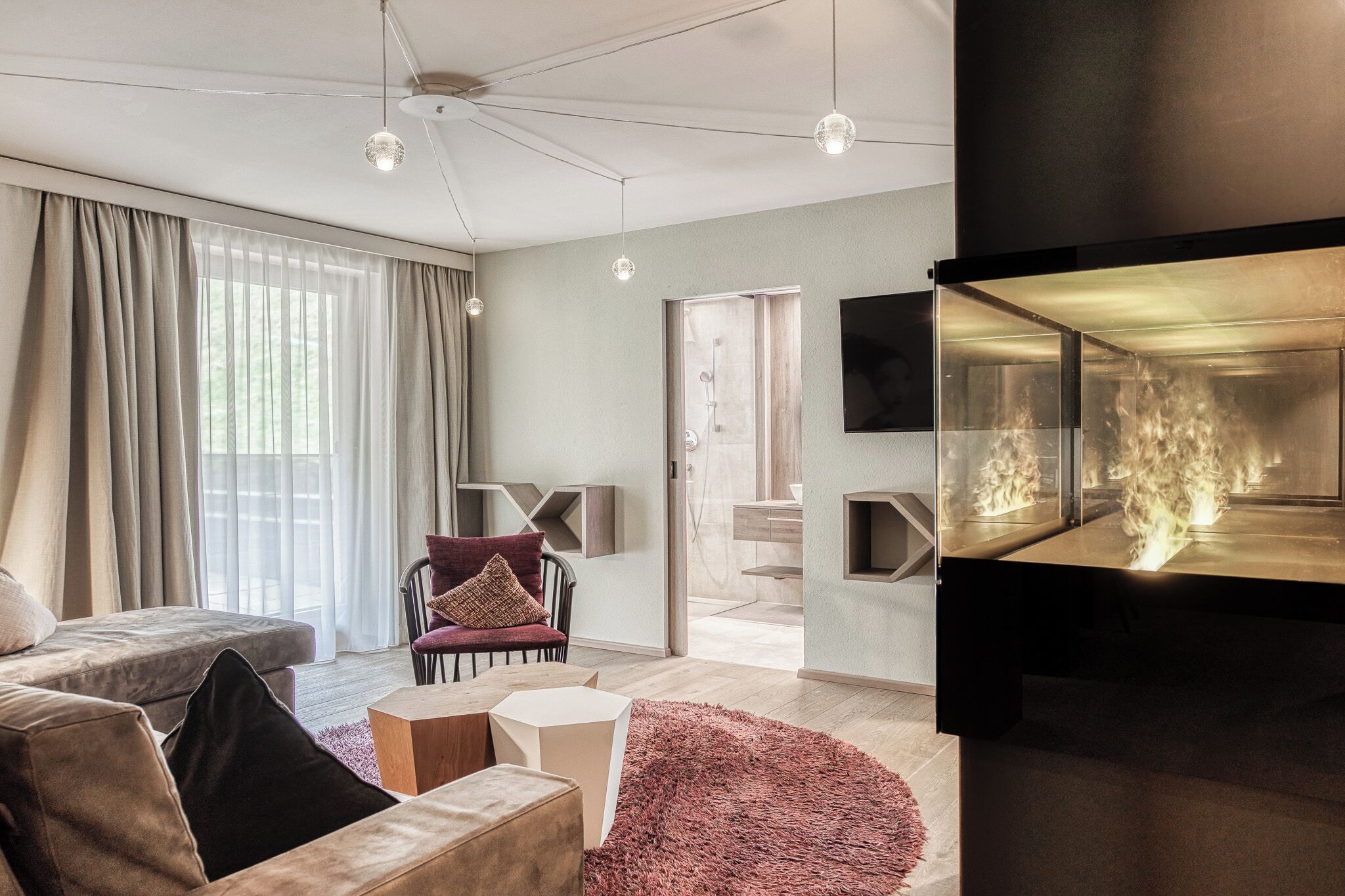 Een moderne woonkamer met een bank, een fauteuil, een open haard en een televisie.