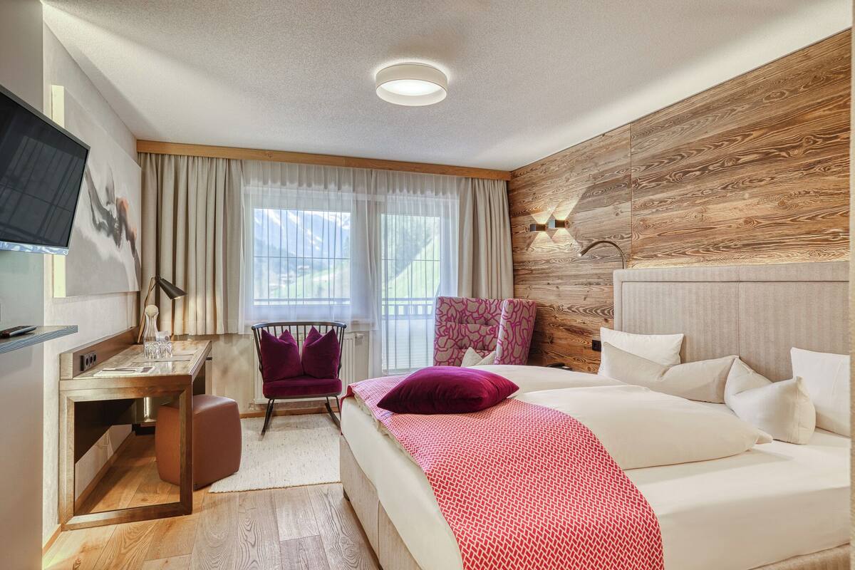 Ein Hotelzimmer mit Bett, Schreibtisch, Stuhl und Fernseher.