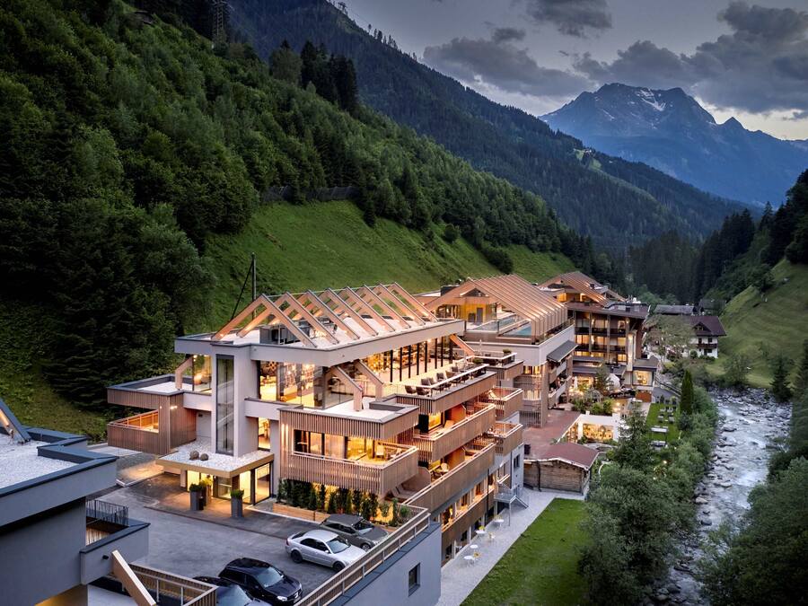 Un hôtel moderne à plusieurs étages, doté de balcons, et situé au bord d’une rivière.