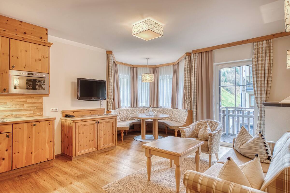 Ein gemütliches Wohnzimmer mit einem Holzschrank, einem Fernseher, einem runden Tisch und einer Couch.