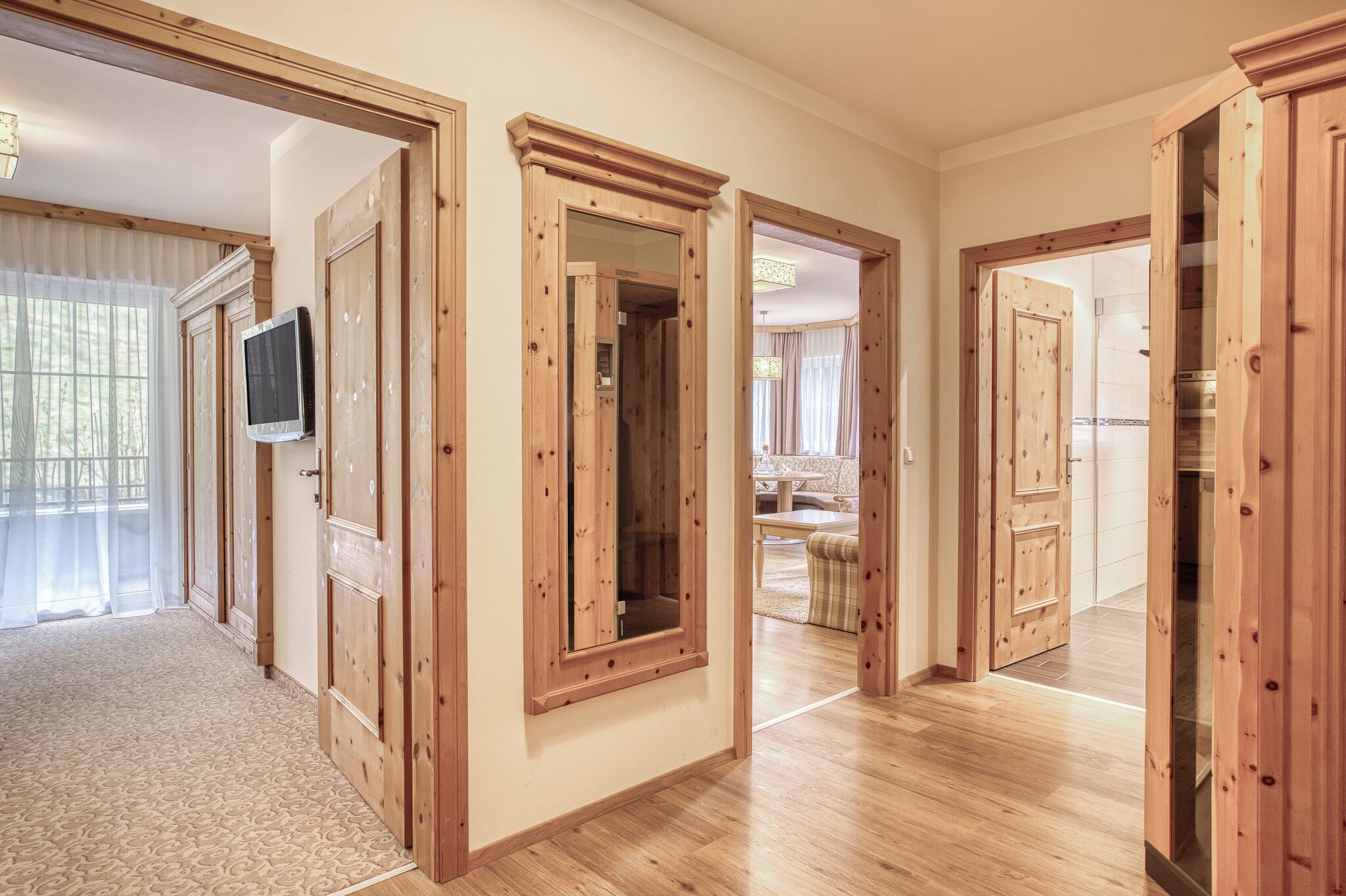 A hallway with wooden doors and a television mounted on the wall.