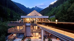 Ein modernes, mehrstöckiges Gebäude mit Holzdeck, Sitzgelegenheiten im Freien und einer Glasfassade.