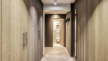 A hallway with wooden paneling, a light fixture, and a view into a bathroom with a toilet and sink.