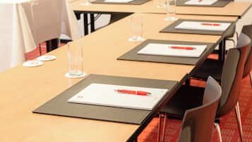 A conference room with long tables, each with a notepad, pen, and glass of water.