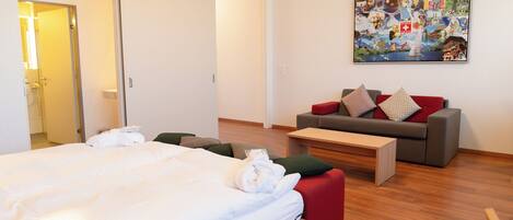 Una habitación de hotel con cama, sofá, una mesa de centro y un cuadro en la pared.