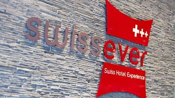 A sign with the text "swissever" and "Swiss Hotel Experience" on a wooden background.