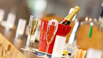 A bar setting with glasses of champagne and a bottle in a red bucket.