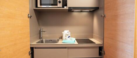 A compact kitchenette with a microwave, sink, and a small refrigerator.