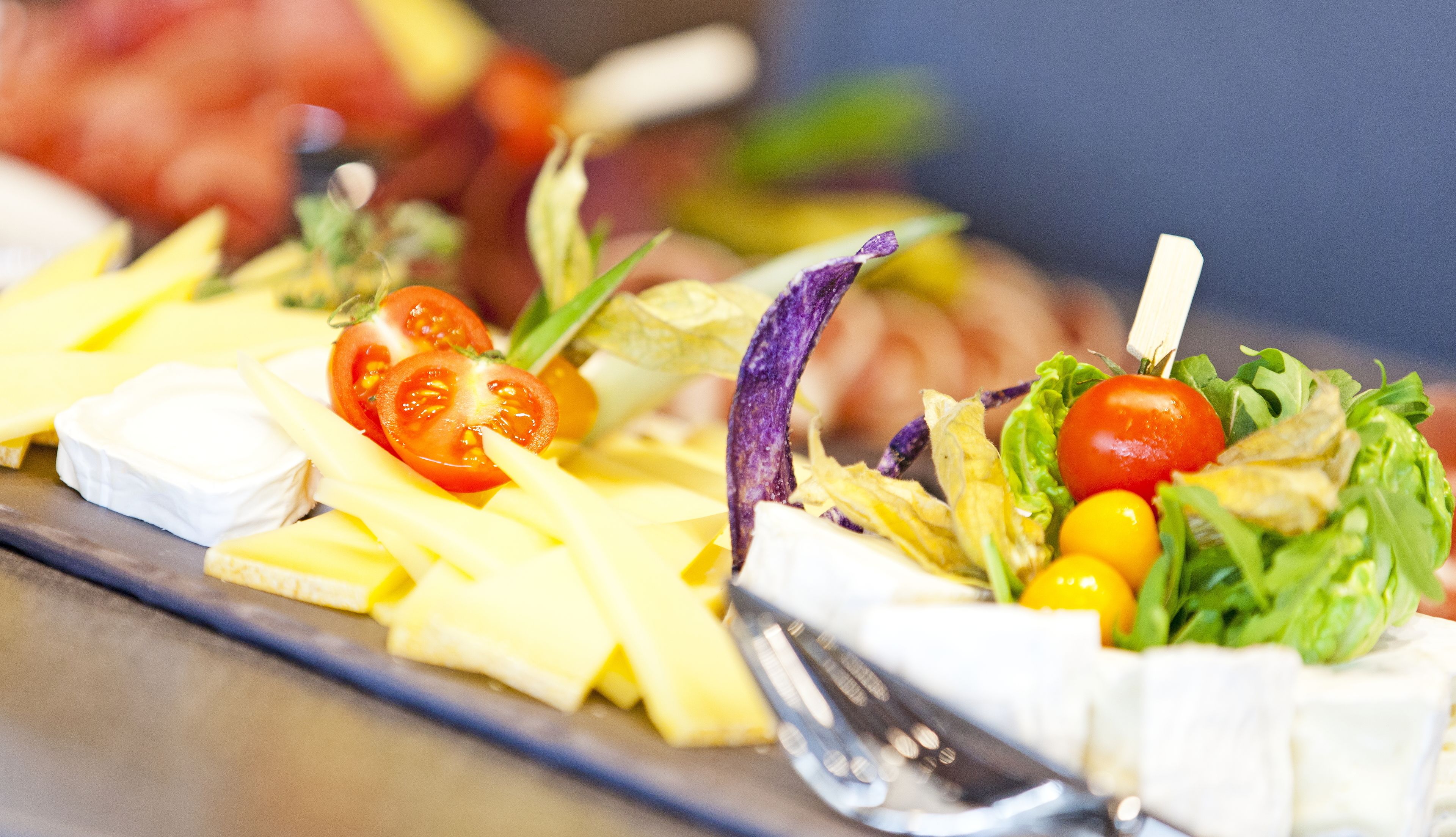 A buffet with various dishes including cheese, tomatoes, and leafy greens.
