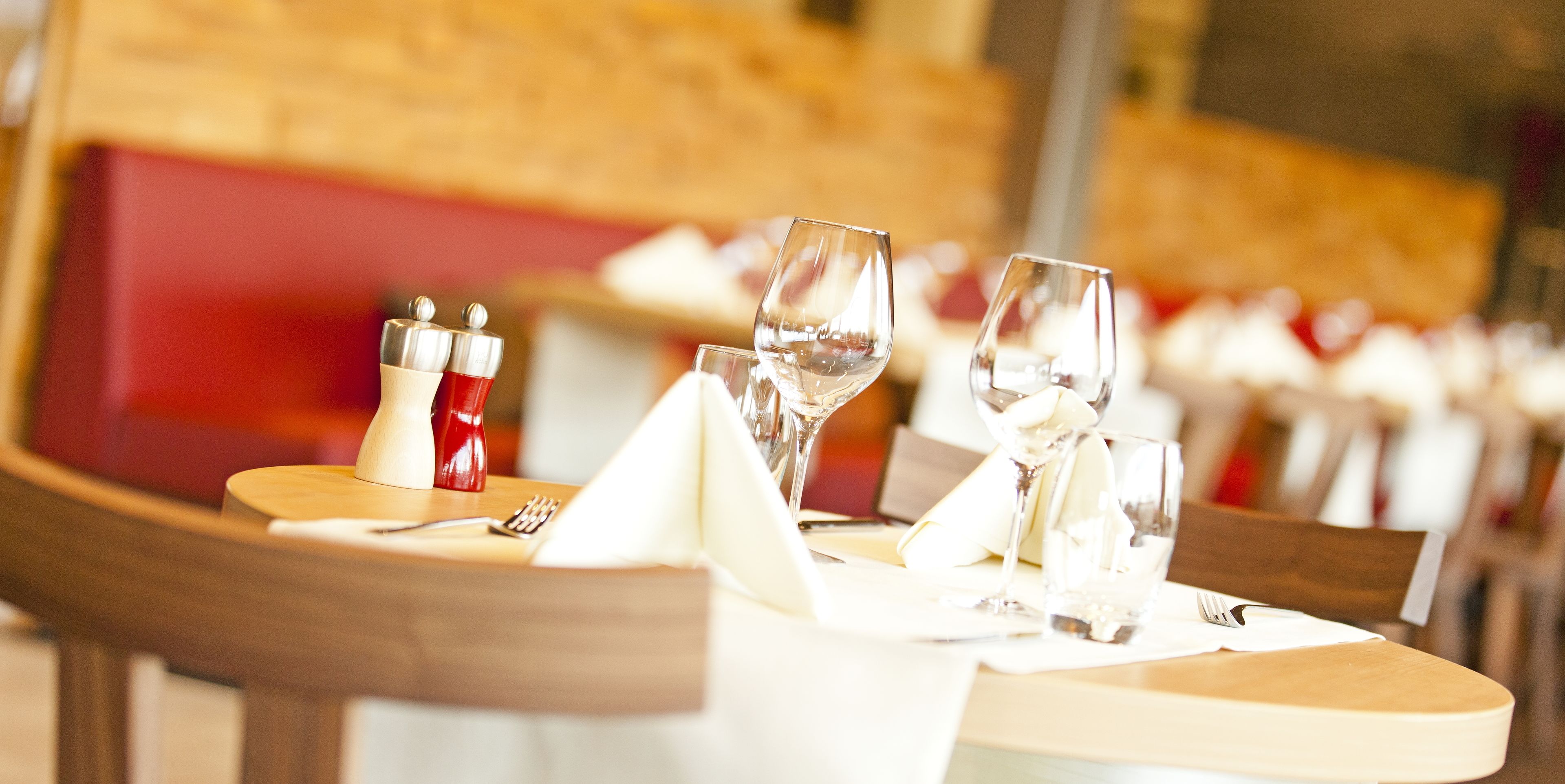 Una mesa de restaurante dispuesta con copas de vino, un vaso de agua y salero y pimentero.