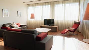 Una sala de estar moderna con un sofá, un televisor, una mesa de centro y una silla roja.