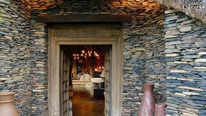 Un pasillo de paredes de piedra que conduce a una zona de estar con chimenea.