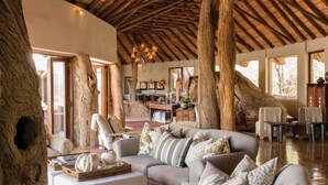 Un amplio salón con un techo alto de madera, un gran tronco de árbol y una acogedora zona de estar.