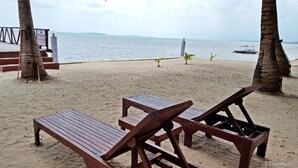 A beach with wooden lounge chairs and a signboard. - Cooper's Beach Resort (Puerto Princesa)