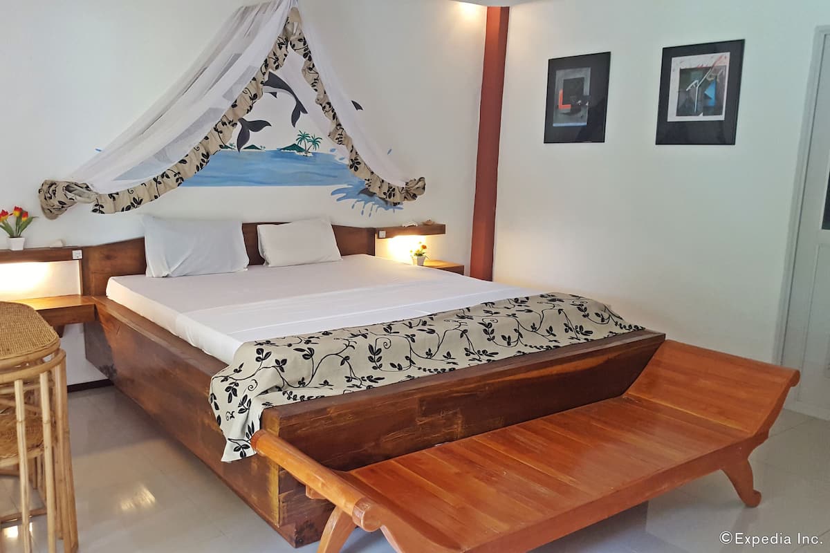 A bed with a canopy, a bedside table with a lamp, a wooden bench, and a small stool.