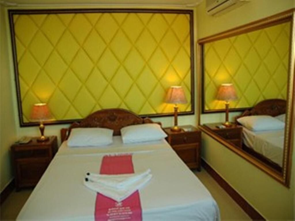 Una habitación de hotel con una cama grande, dos mesitas de noche y un espejo.