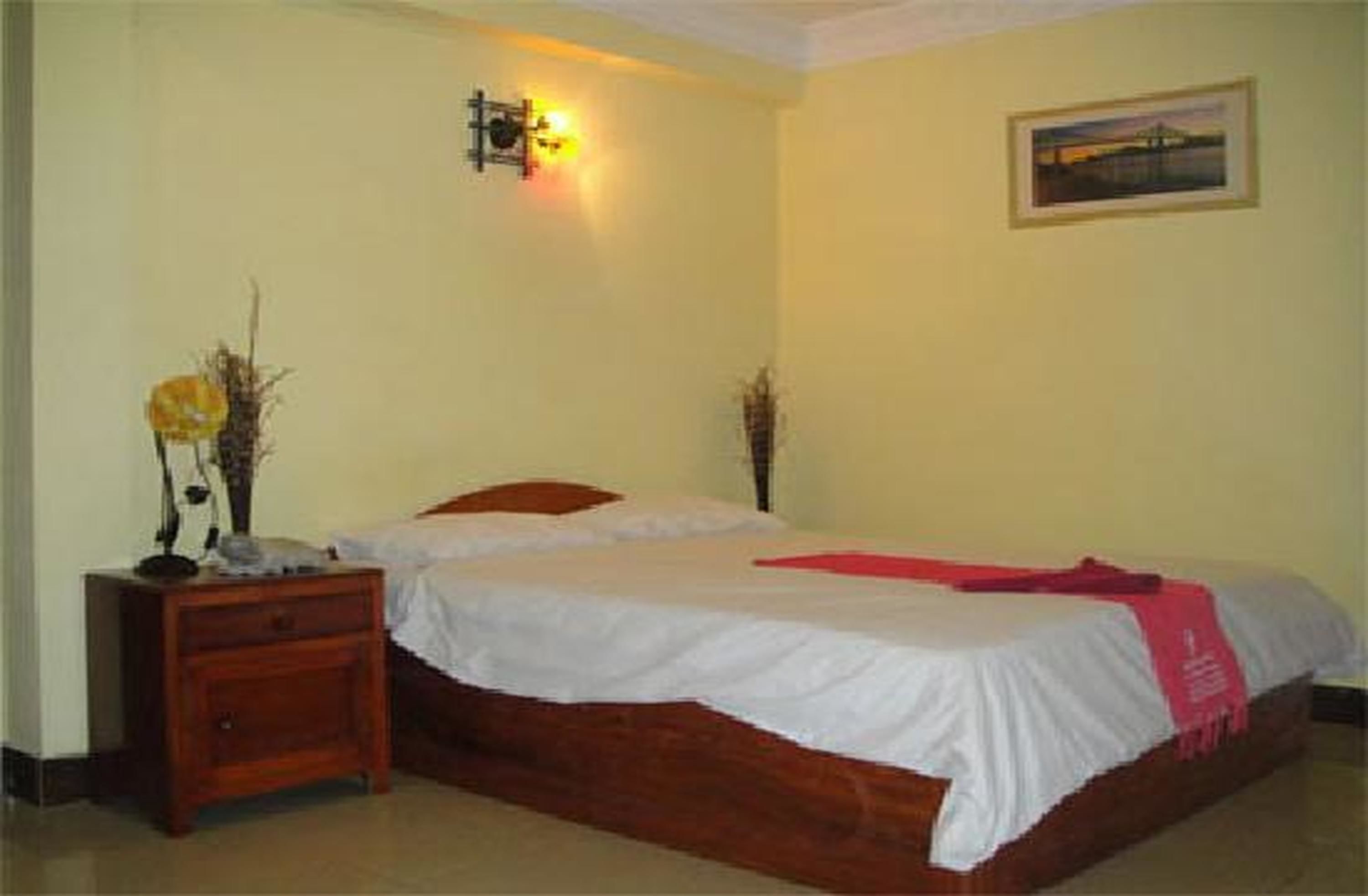 Un dormitorio con cama de madera, una mesita de noche, una lámpara y una lámpara de pared.