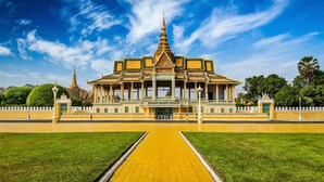 A large, symmetrical building with a central tower and multiple smaller structures, surrounded by a well-maintained lawn and a paved walkway. - Sky Park Guesthouse (Phnom Penh)