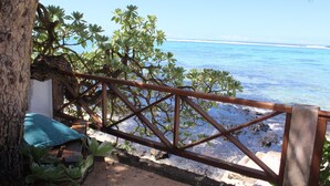 Una terraza de madera con barandilla de metal que da a una playa.