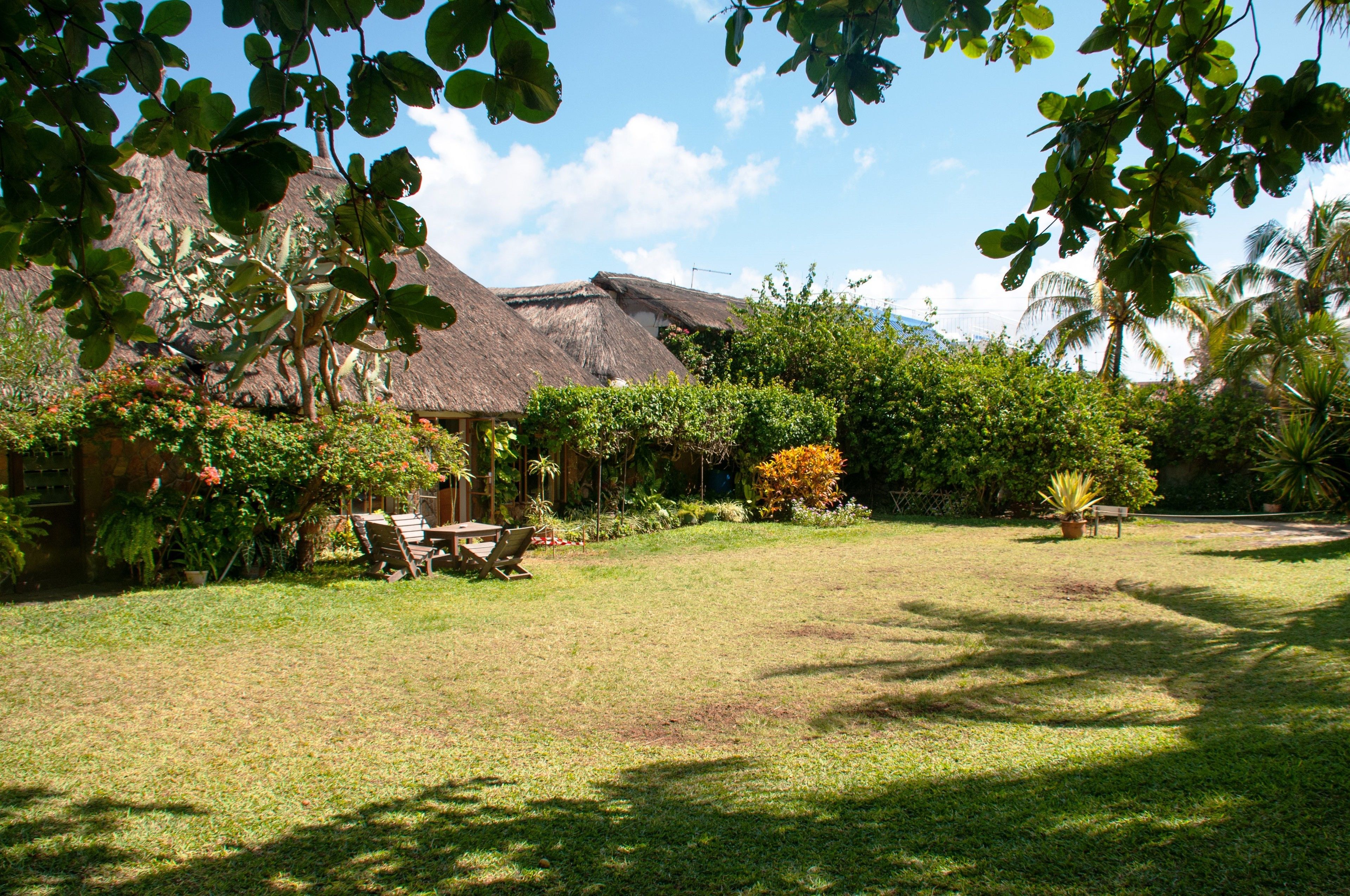 A thatched-roof house with a lawn and outdoor furniture.