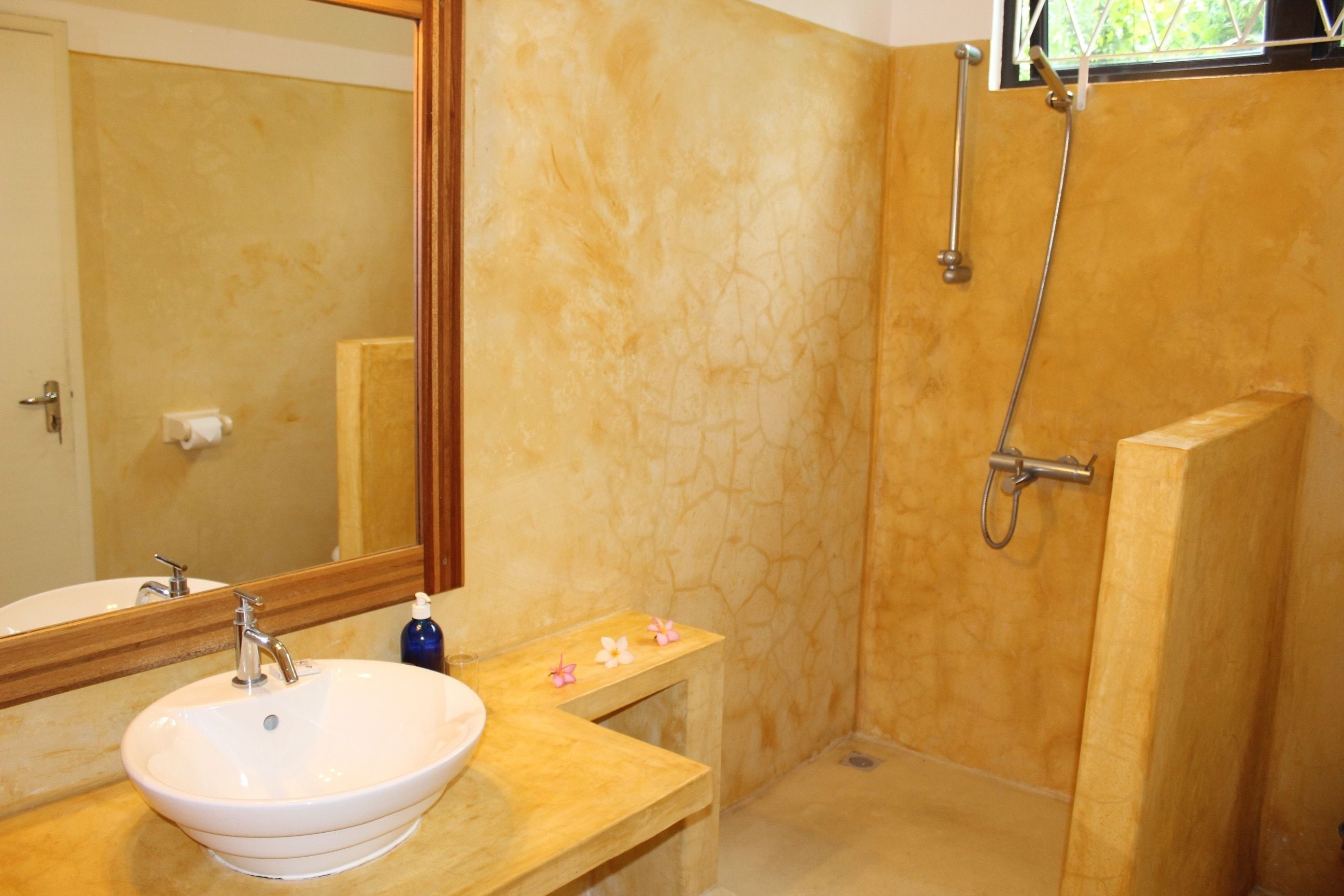 A bathroom with a sink, mirror, and shower.