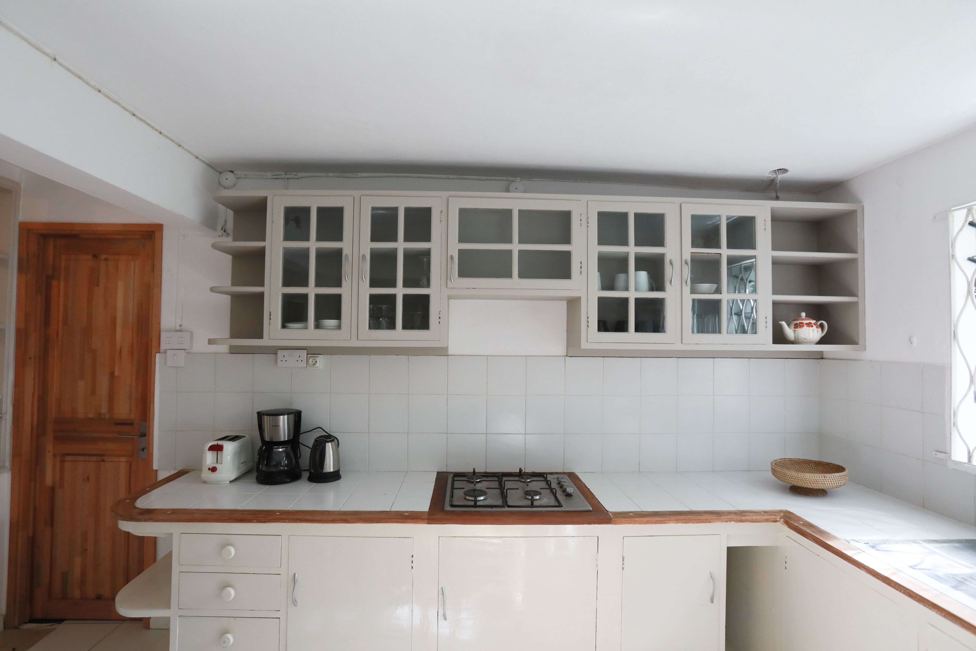 A kitchen with white cabinets, a wooden countertop, a gas stove, a coffee maker, and a basket.