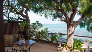 Un patio con mesa y sillas, con vista a la playa y al mar.