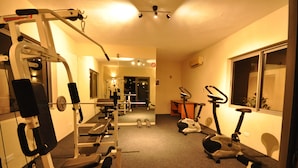 A gym with various exercise equipment including treadmills, a weight machine, and dumbbells.