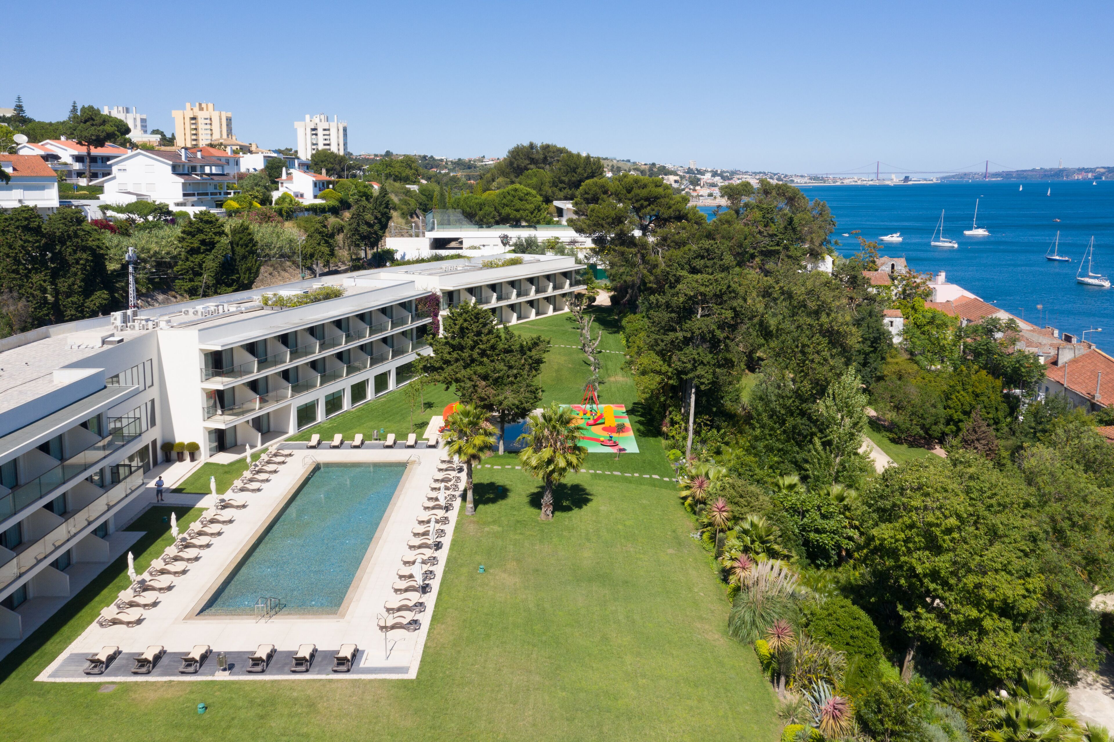 Um hotel com piscina, várias varandas e vista para o mar.