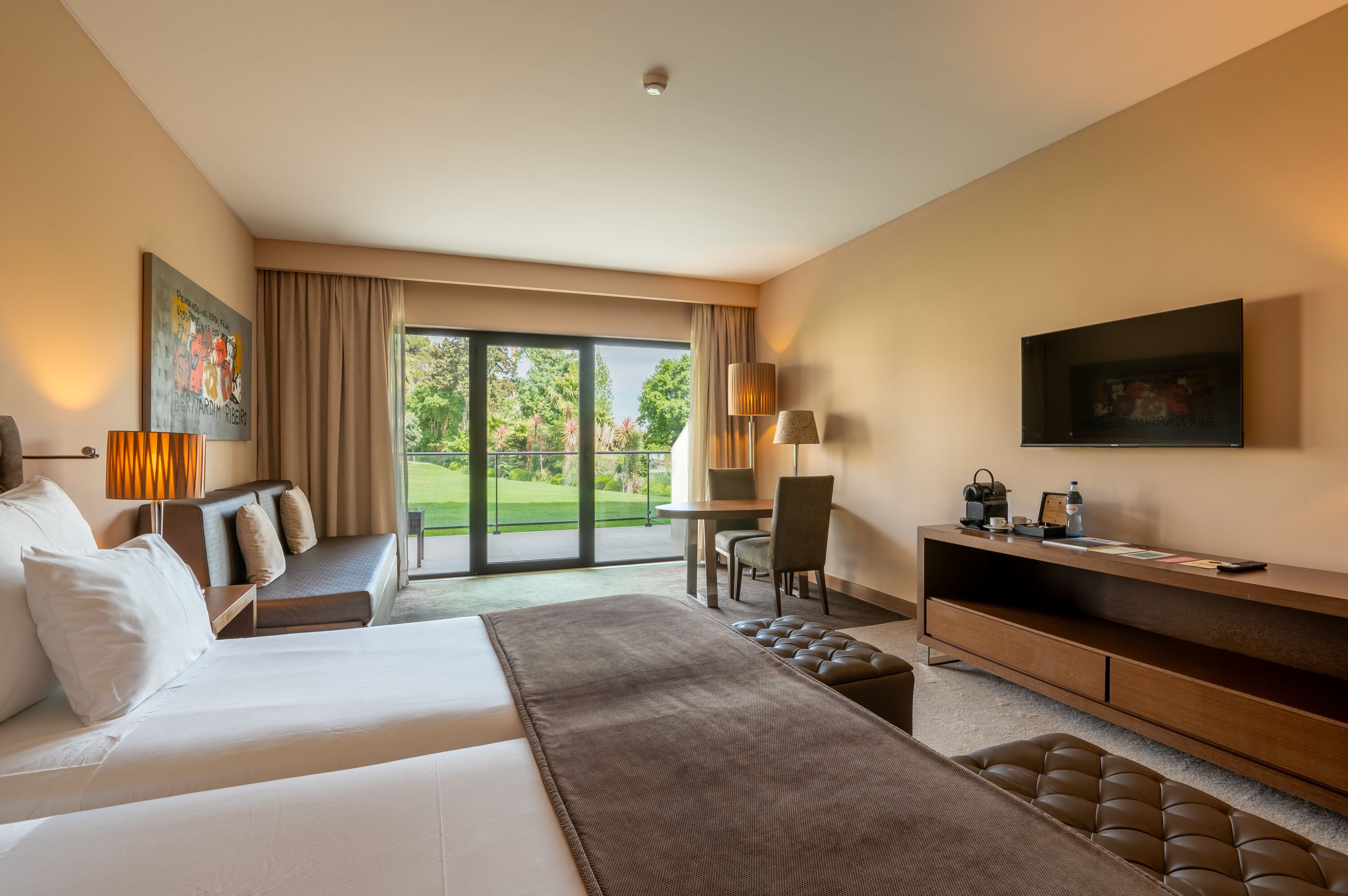 Habitación de hotel con una cama grande, un escritorio, una silla, un sofá y un televisor.