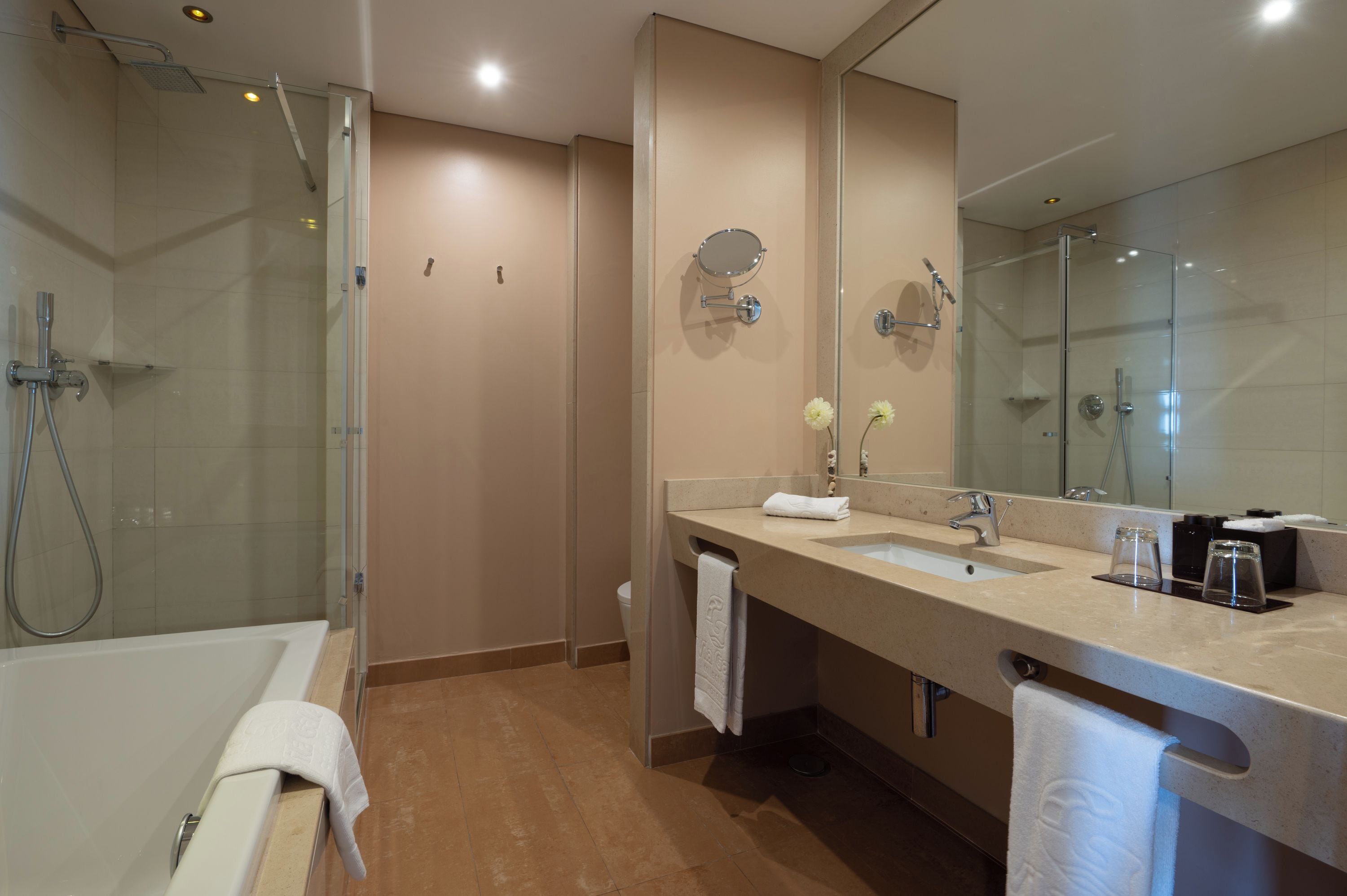 A modern bathroom with a glass-enclosed shower, a bathtub, and a vanity with a large mirror.
