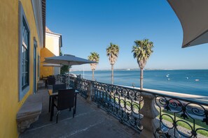Un balcón con mobiliario exterior, vista al mar y palmeras.